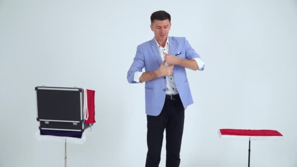 Magiker i kostym visar ett trick med bollar på en vit bakgrund — Stockvideo