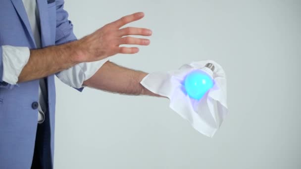 Kouzelník v obleku ukazuje trik s lampou na bílém pozadí — Stock video