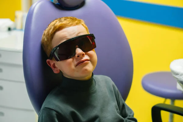 Scared red-haired boy crying at reception at dentist in dental chair. Pediatric dentistry — Stock Photo, Image