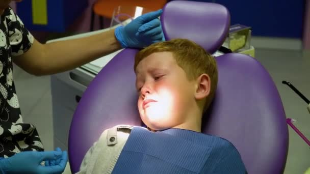 Scared red-haired boy crying at reception at dentist in dental chair. Pediatric dentistry — Stok video