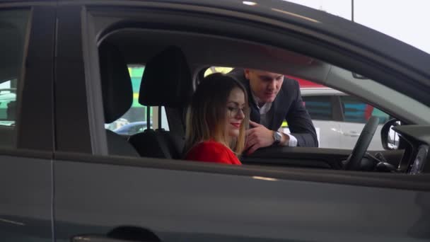 Consultor em uma concessionária de automóveis apresenta um carro para uma mulher de negócios — Vídeo de Stock