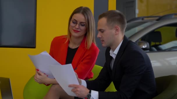 Seller and buyer are studying the contract of sale of the car. Beautiful woman buys a car — 비디오