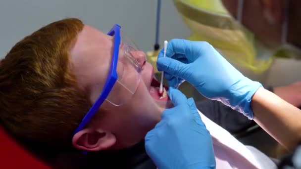 Il dentista cura i denti di un ragazzo rosso spaventato — Video Stock