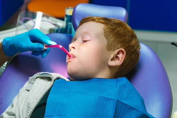 Ein verschreckter rothaariger Junge weint an der Rezeption beim Zahnarzt im Zahnarztstuhl. Kinderzahnheilkunde — Stockfoto