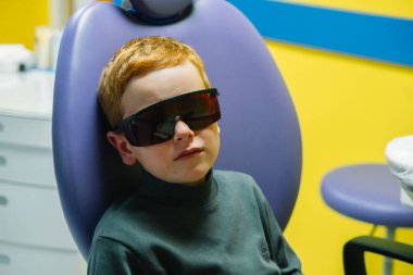 Scared red-haired boy crying at reception at dentist in dental chair