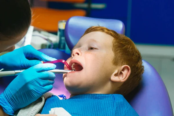 Niño pelirrojo asustado llorando en la recepción en el dentista en la silla dental —  Fotos de Stock