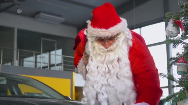 Санта Клаус в автосалоні вибирає машину з подарунком. — стокове відео