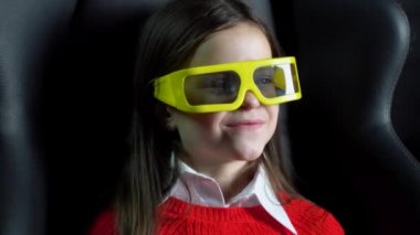 Küçük kız sinemada 3 boyutlu gözlüklü heyecanlı bir film izliyor.