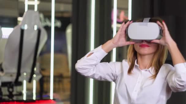 A woman wearing virtual reality glasses. Virtual reality installation on the background — Stock Video