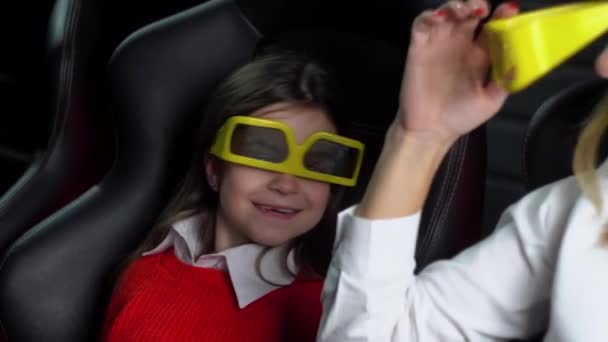 Женщина с маленькой дочерью смотрит захватывающий фильм в кинотеатре в 3D очках — стоковое видео