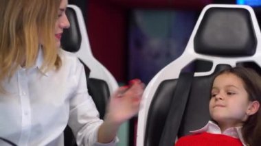 Kadın ve küçük kız sanal gerçeklik simülatörü oynamaya hazırlanıyorlar.