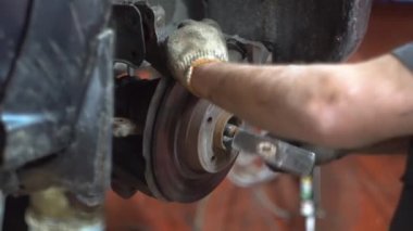 Tamirci adam araba tamirhanesinde araba tamir ediyor.