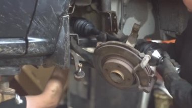 Tamirci adam araba tamirhanesinde araba tamir ediyor.