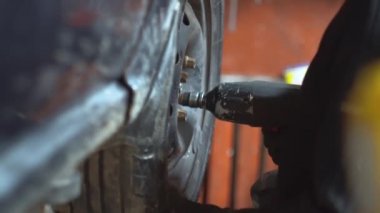 Tamirci adam araba tamirhanesinde araba tamir ediyor.