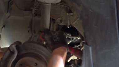 Tamirci adam araba tamirhanesinde araba tamir ediyor.