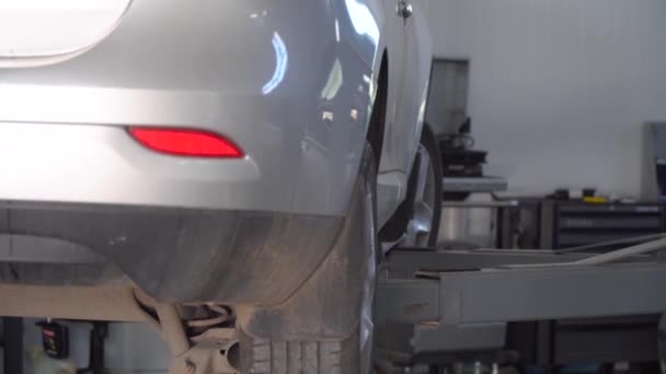 Plataforma hidráulica dejando un coche abajo en el taller de reparación de automóviles. Servicio, reparación y mantenimiento de automóviles — Vídeo de stock