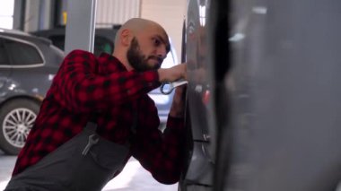 Sakallı tamirci araba tamirhanesinde araba tamir ediyor. Araba servisi, onarım ve bakım