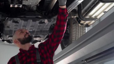 Tamirci adam araba tamirhanesinde araba tamir ediyor. Araba servisi, onarım ve bakım