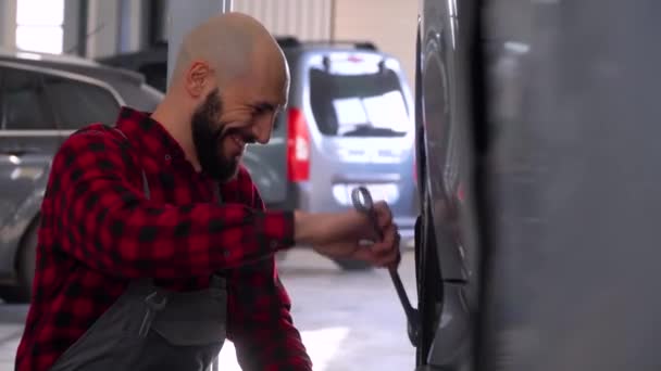 Lindo mecánico de reparación de un coche en el taller de reparación de coches. Servicio, reparación y mantenimiento de automóviles — Vídeos de Stock