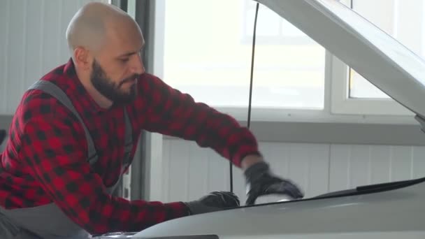 Μηχανικός επισκευάζει ένα αυτοκίνητο σε συνεργείο αυτοκινήτων. Υπηρεσία, επισκευή και συντήρηση αυτοκινήτων — Αρχείο Βίντεο
