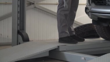 Tamirci anahtarı düşürür. Tamirci adam araba tamirhanesinde araba tamir ediyor.