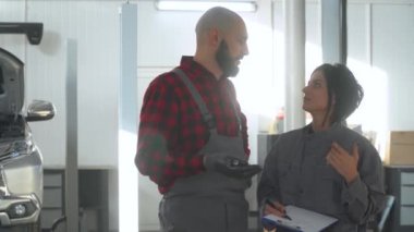 İki profesyonel tamirci kadın ve erkek araba tamirhanesinde. Araba servisi, onarım ve bakım