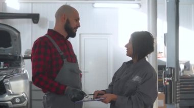 İki profesyonel tamirci kadın ve erkek araba tamirhanesinde. Araba servisi, onarım ve bakım