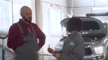 İki profesyonel tamirci kadın ve erkek araba tamirhanesinde. Patron kadın astlarını azarlıyor.
