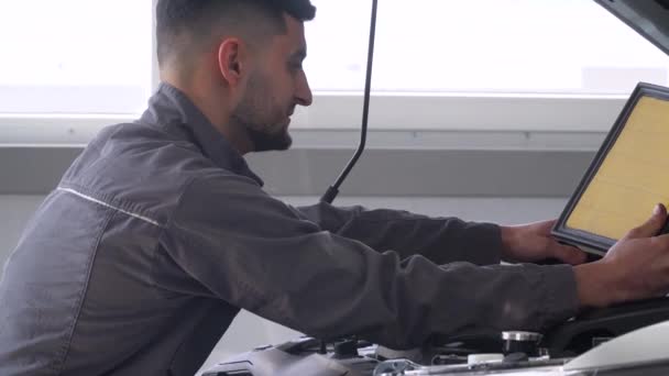 Mécanicien professionnel réparant une voiture dans un atelier de réparation automobile. Service de voiture, réparation et entretien — Video