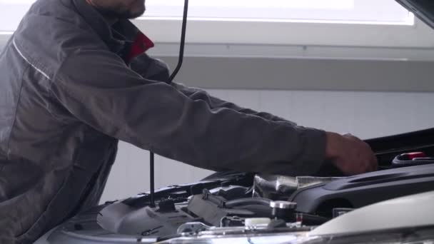Mécanicien professionnel réparant une voiture dans un atelier de réparation automobile. Service de voiture, réparation et entretien — Video