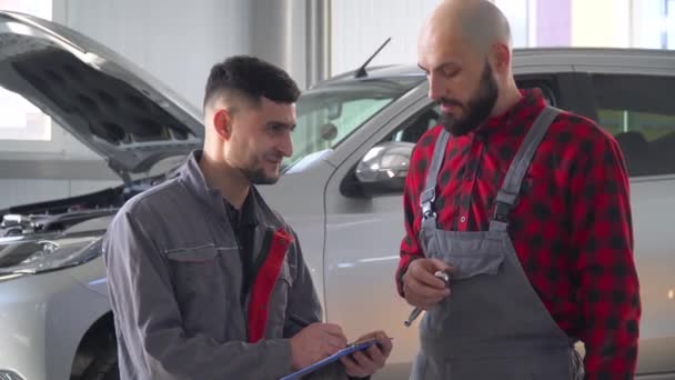Två professionella mekaniker reparera en bil i bilverkstad. Bilservice, reparation och underhåll — Stockvideo