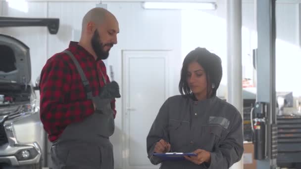 Deux mécaniciens professionnels femmes et hommes dans un atelier de réparation automobile. . Patron femme gronde son subordonné — Video