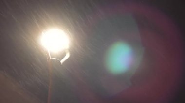 City lantern in falling snow at Christmas night. Lamp post, with snow falling in calm winter scene in the city