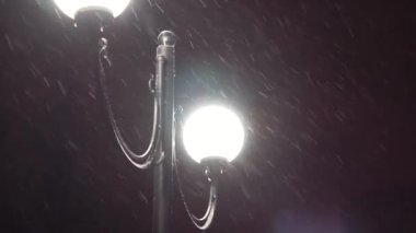 City lantern in falling snow at Christmas night. Night winter street lamp with falling snow