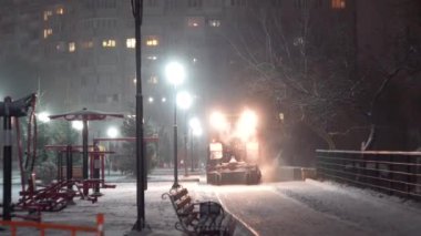 Tractor cleaning snow in the night city