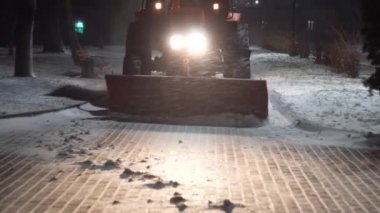 Tractor cleaning snow in the night city