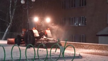 Tractor cleaning snow in the night city