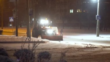 Tractor cleaning snow in the night city