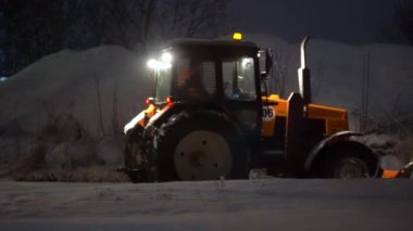 Tractor cleaning snow in the night city