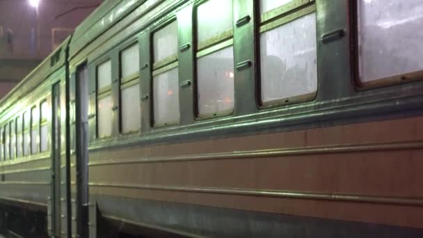 Heavy snow fall at railroad tracks. Train at night light of railway station — Stock Video