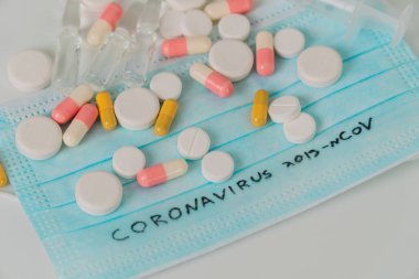 Surgical mask protective mask with CORONAVIRUS text. Virus 2019-n CoV in Wuhan, China. Tablets, mask, syringe