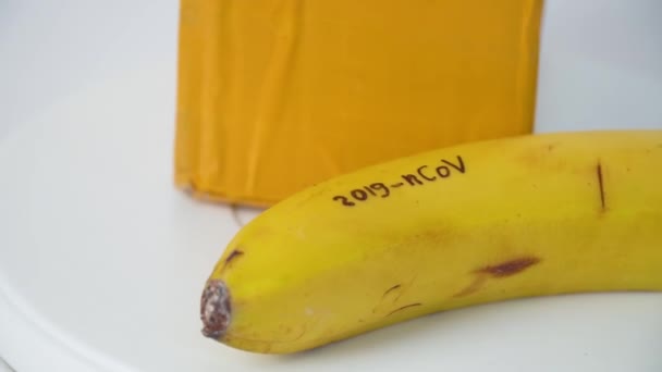 Banana with CORONAVIRUS text and package from China. Virus 2019-n CoV in Wuhan — ストック動画