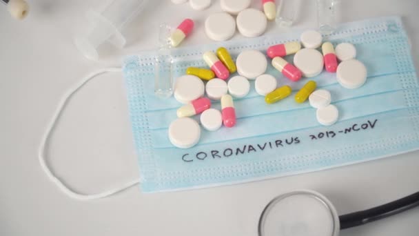 Хирургическая маска защитная с текстом CORONAVIRUS. Вирус 2019-n CoV в Ухане, Китай. Стетоскоп, таблетки, маска, шприц — стоковое видео