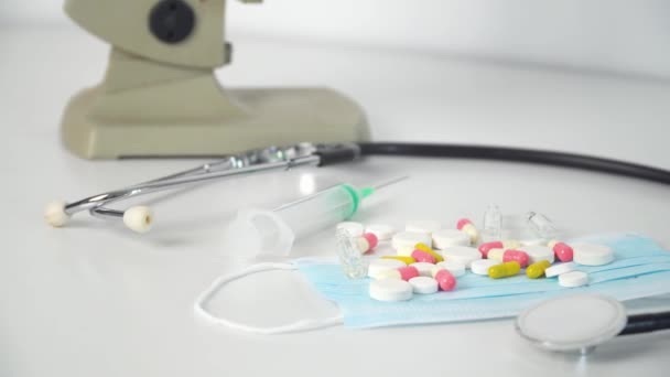 Chirurgische Maske Schutzmaske Stethoskop, Tabletten und Spritze auf weißem Hintergrund — Stockvideo