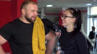 Güçlü kaslı adam ve kız spor salonunda konuşuyor.