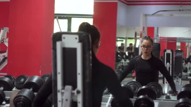 Όμορφη κοπέλα με γυαλιά στο αθλητικό κέντρο κάνει διάφορες ασκήσεις. — Αρχείο Βίντεο