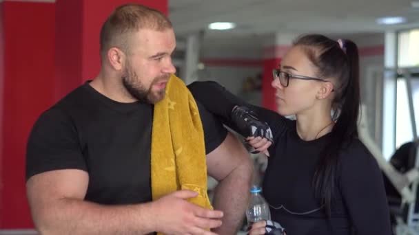 Silný svalnatý muž s dívkou mluvit v tělocvičně — Stock video