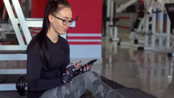 Mladá dívka pomocí smartphone v tělocvičně — Stock video