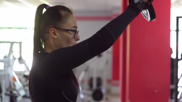 Hermosa chica en gafas en el club deportivo hace diferentes tipos de ejercicios — Vídeo de stock