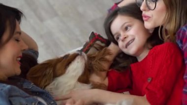 İki mutlu kadın ve köpek yatakta sarılıyor.